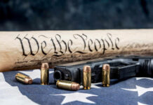 Gun, bullets, Constitution scroll on American flag.