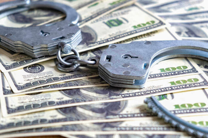 shutterstock_1934311637.jpg featured image Handcuffs on a pile of one hundred dollar bills.