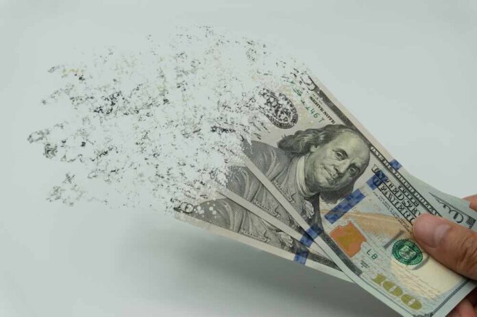 shutterstock_2122253927.jpg featured image Hundred-dollar bills disintegrating in hand.