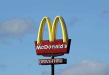 McDonald’s drive-thru sign against a blue sky.