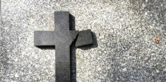Broken black cross on a gray surface.