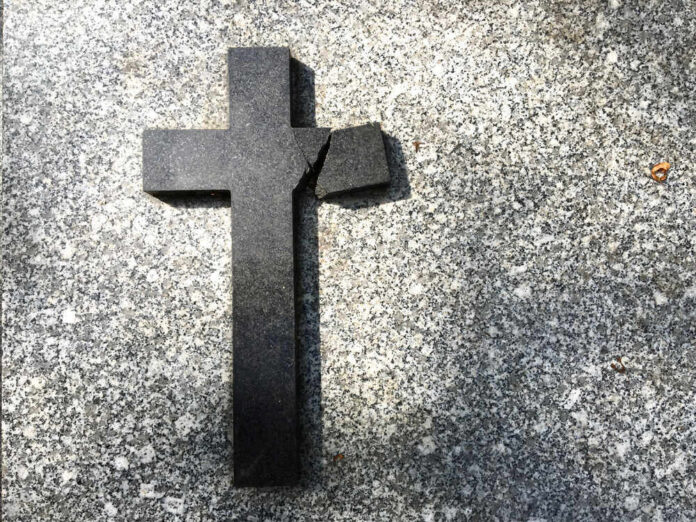 Broken black cross on a gray surface.