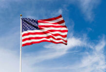 American flag waving against a blue sky.