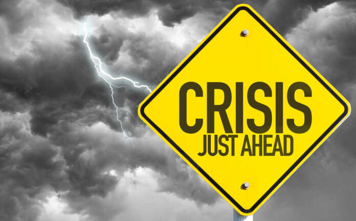 Yellow sign reading Crisis Just Ahead with stormy sky