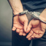 Person with handcuffs behind their back.
