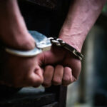Close-up of hands in handcuffs behind back.
