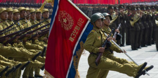 Soldiers marching with rifles and a flag banner
