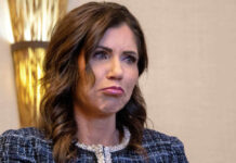 Kristi Noem with long dark hair frowns slightly.