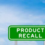 Green sign with product recall text and sky background