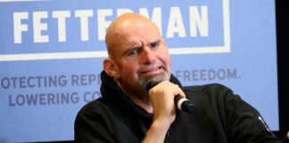 Bald man with goatee holding microphone.