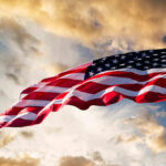 American flag waving under a cloudy sky.