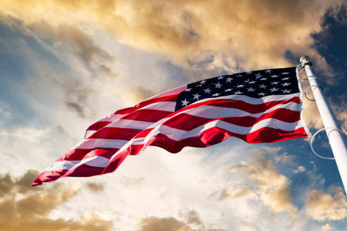 shutterstock_360951227.jpg featured image American flag waving under a cloudy sky.