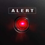 Red alert light against black background, text ALERT.