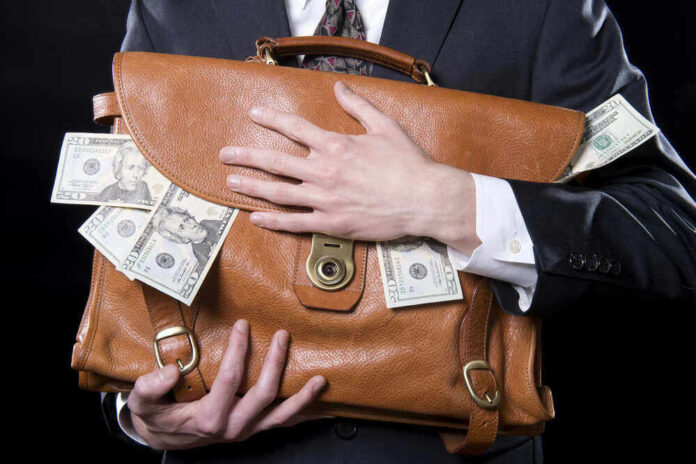 shutterstock_133129220-1.jpg Person clutching leather bag with money sticking out