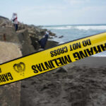 Yellow police tape by rocky ocean shore