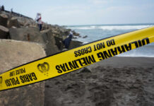 Yellow police tape by rocky ocean shore