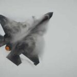 F-35 jet performing an aerial maneuver with smoke trailing behind