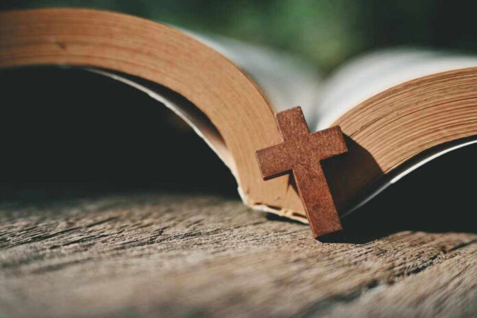 shutterstock_2422584703.jpg Open Bible with a wooden cross on it