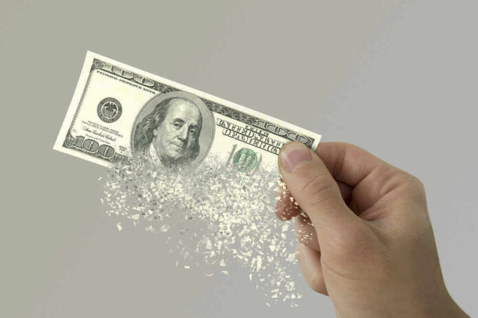 Hand holding a disintegrating hundred dollar bill