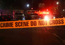 Crime scene tape with emergency vehicles in background