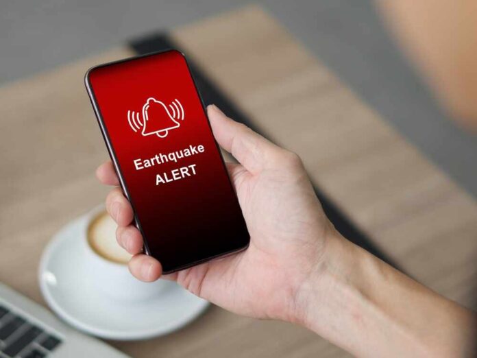 Hand holding a smartphone displaying an earthquake alert notification