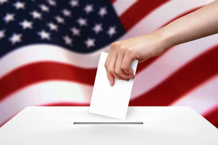 Hand dropping ballot into box, American flag background