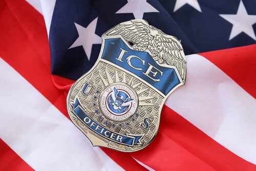 shutterstock_2440926905.jpg ICE officer badge resting on an American flag
