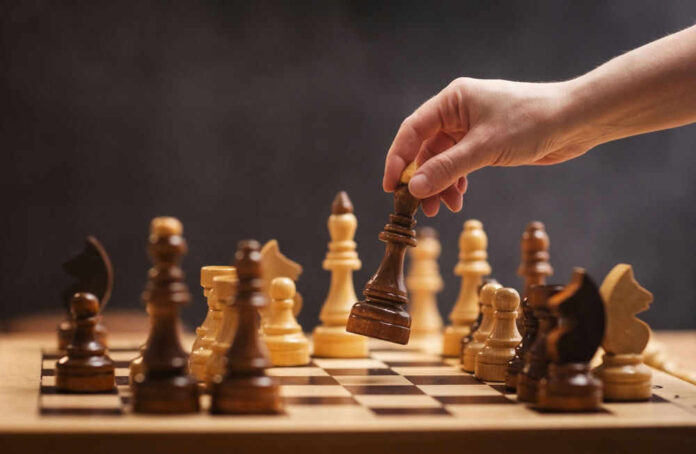 shutterstock_2463856077.jpg Hand moving chess piece during a game