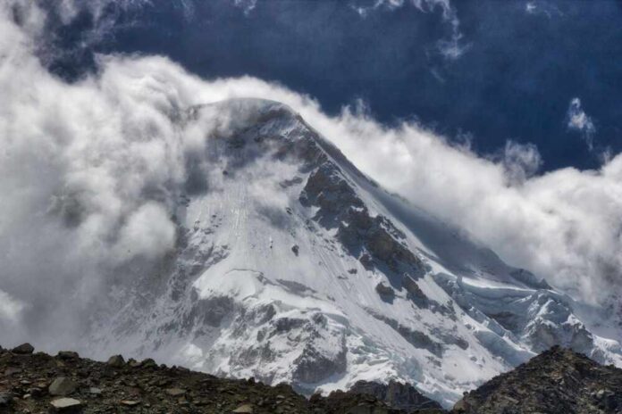 Snow-covered mountain peak partially obscured by clouds