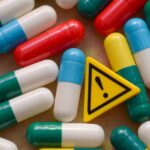 Colorful capsules scattered around a yellow warning sign