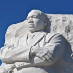Martin Luther King Jr. statue against clear blue sky.