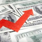 A red arrow indicating growth over scattered hundred dollar bills