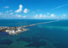 Aerial view of a coastal area with a long bridge extending over turquoise waters