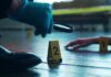 A detective examining evidence at a crime scene with markers on the floor