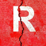 Cracked red wall with white letter R.
