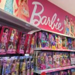 Shelves filled with various Barbie dolls and accessories in a toy store