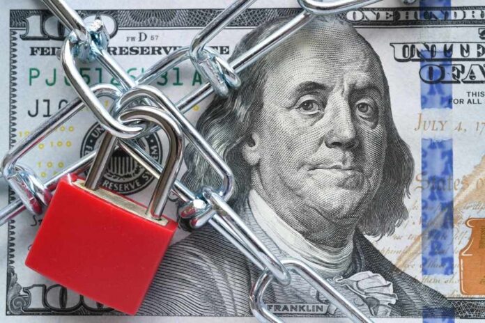shutterstock_2297559635.jpg A red padlock and chain over a hundred dollar bill featuring Benjamin Franklin