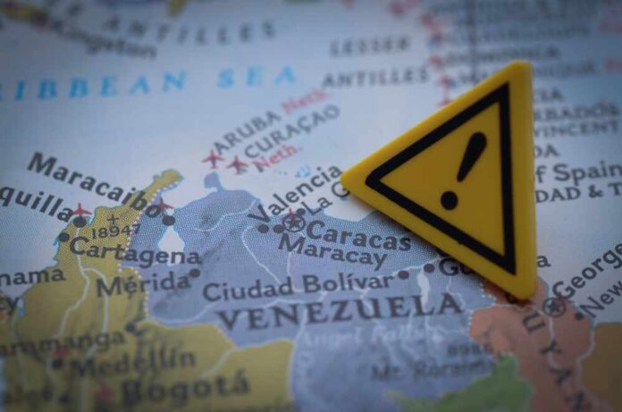A close-up of a map showing Venezuela with a yellow warning sign