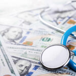 Health Care Crisis: Americans CUTTING Essentials A stethoscope resting on a pile of hundred-dollar bills
