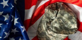 Camouflage military cap resting on an American flag