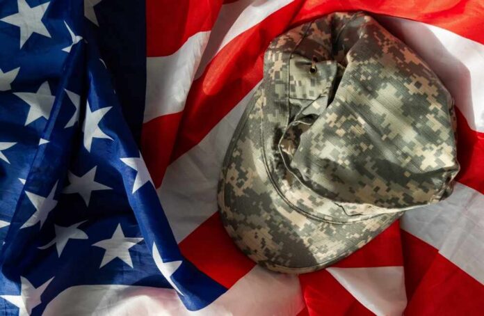 shutterstock_2532439577.jpg Camouflage military cap resting on an American flag