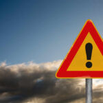 Doctors Said No — She’s Going Anyway A triangular warning sign with an exclamation mark against a cloudy sky