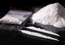 A bag of white powder next to two lines of powder on a reflective surface