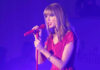 Taylor Swift in a red dress performing on stage.