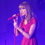 Taylor Swift in a red dress performing on stage.