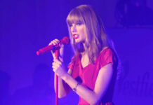 Taylor Swift in a red dress performing on stage.