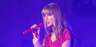 Taylor Swift in a red dress performing on stage.