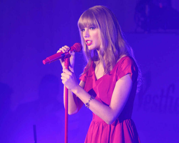 Taylor Swift in a red dress performing on stage.