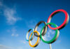 Five colorful Olympic rings against a clear blue sky