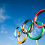 Olympic Committee Agrees With Trump Five colorful Olympic rings against a clear blue sky